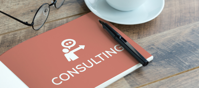 Caderno com a palavra consulting sobre a mesa, representando consultoria de marketing digital para pequenas empresas.