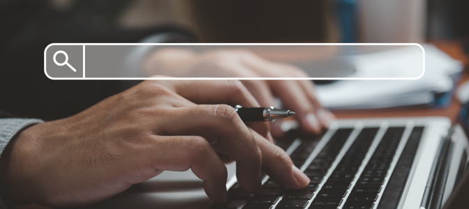 Mãos digitando em um notebook com ícone de barra de busca, representando pesquisa sobre quanto custa fazer um site
