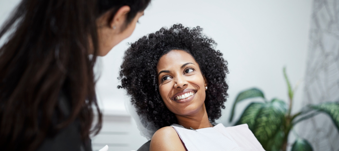 Paciente em atendimento odontológico sorrindo em consultório, representando anúncios e estratégias de tráfego pago para dentistas focadas em atração de pacientes.