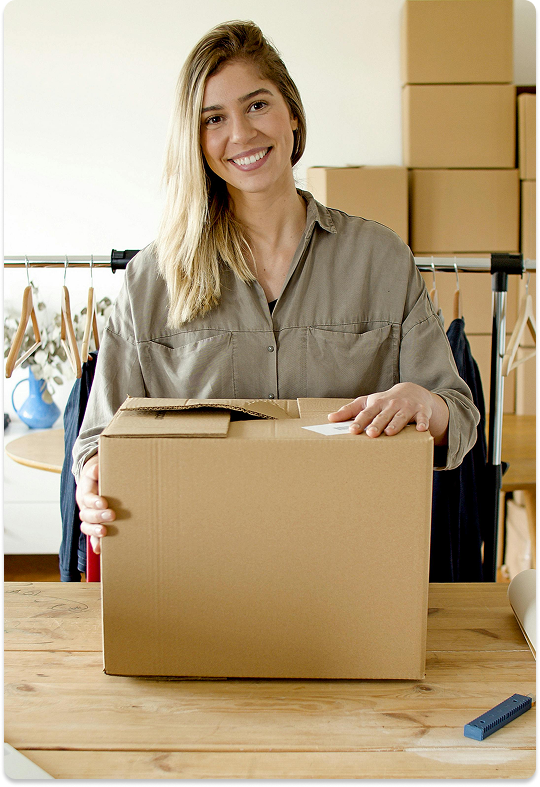 Empreendedora organizando pedidos de uma loja virtual, com caixa de envio sobre a mesa, representando e-commerce profissional integrado a pagamentos e logística.